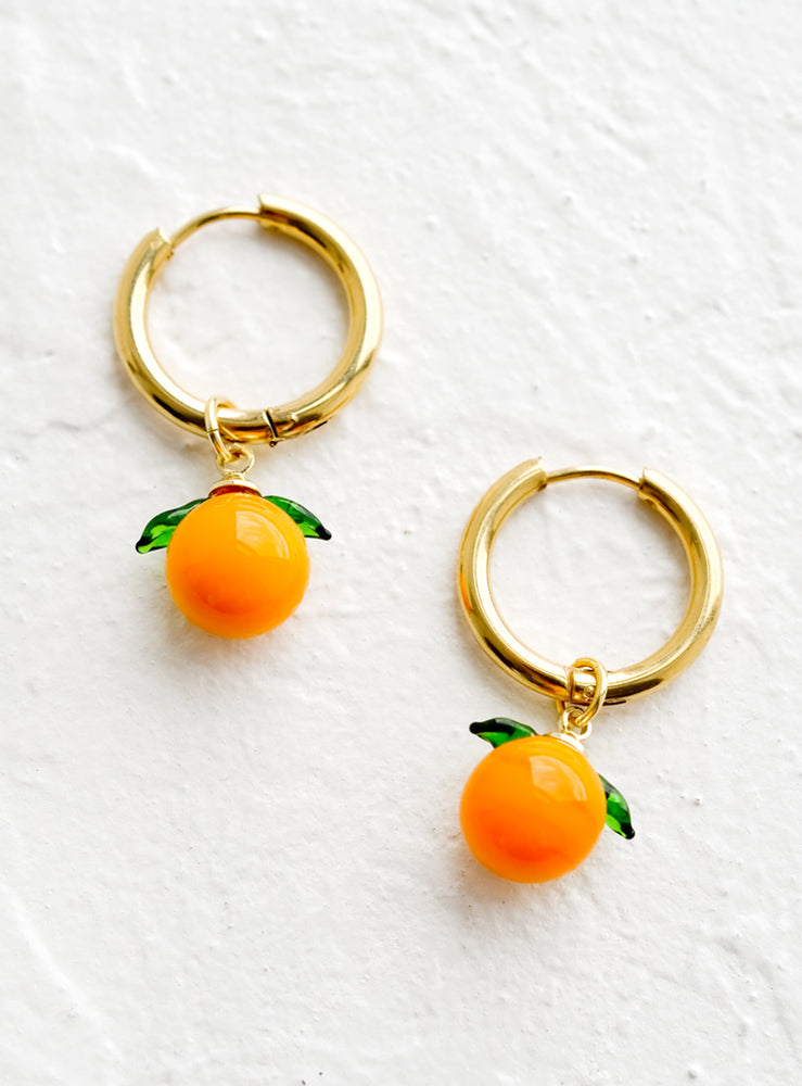 Gold huggie hoop earrings with glass tangerine charms.