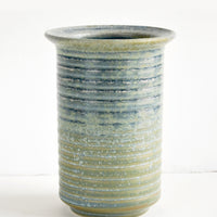 3: A tall ceramic vase in a rustic blue-green glaze with ribbed texture and lipped opening.