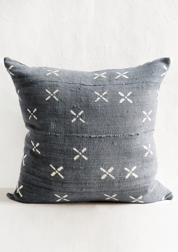 A dusty blue mudcloth pillow with white X pattern.