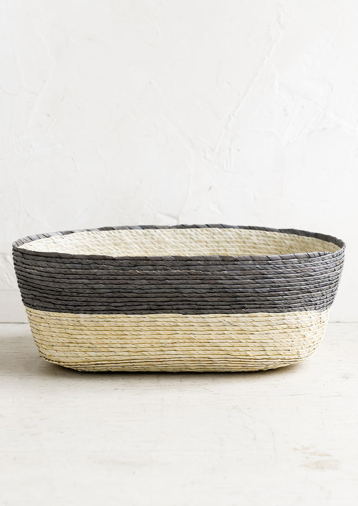 A two-tone oval shaped storage basket in natural and mineral blue-grey.