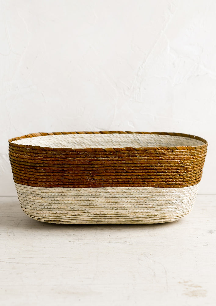 Ochre: A two-tone oval shaped storage basket in natural and ochre.