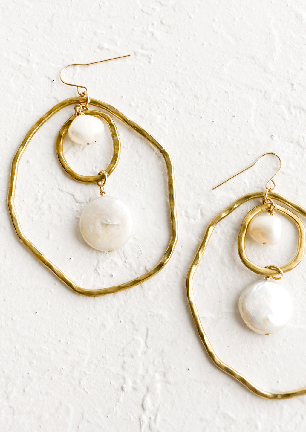 1: A pair of gold earrings with freeform hoops and floating pearls.