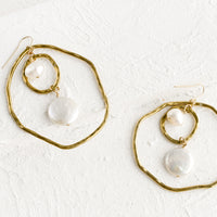 2: A pair of gold earrings with freeform hoops and floating pearls.