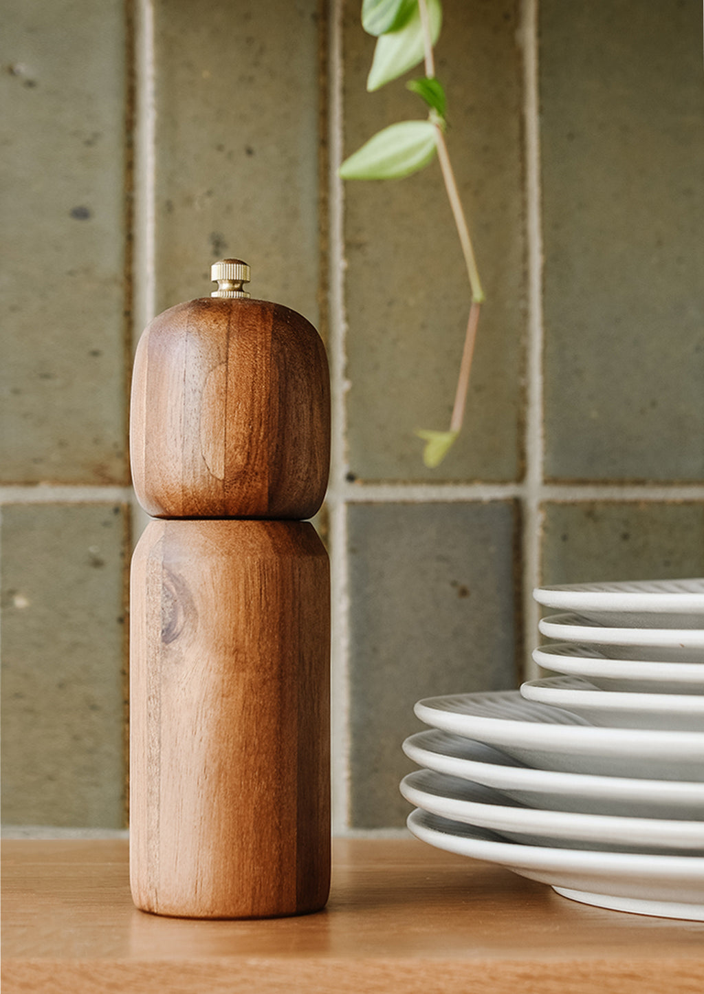 2: A wooden pepper grinder on a kitchen shelf.