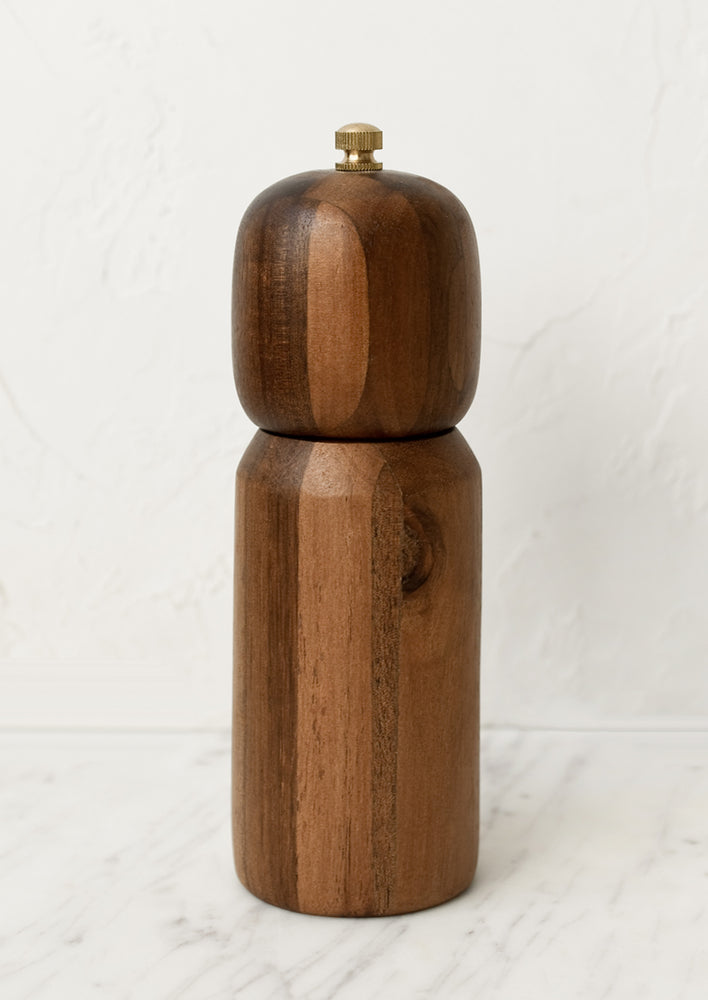 1: A wooden pepper mill with rounded shape and brass tip.