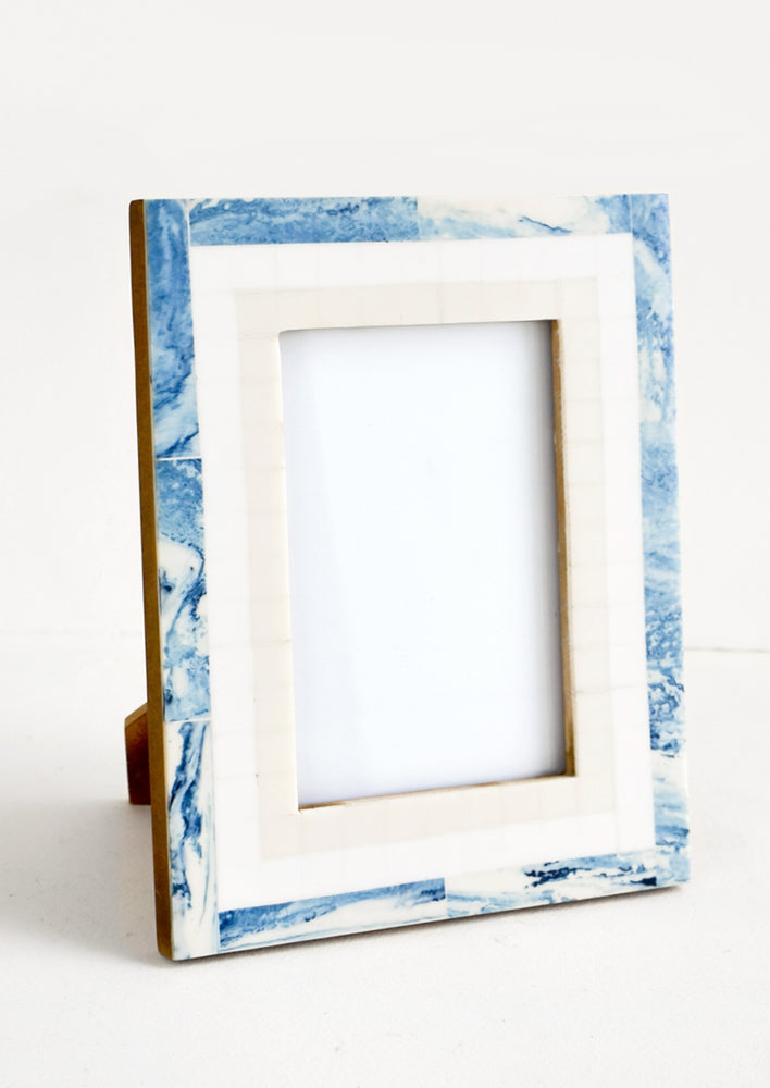 A decorative picture frame with a tiled border in marbled blue, white and cream.