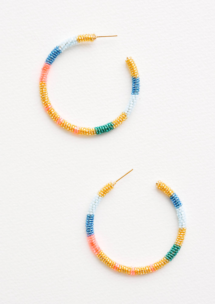 Hoop earrings with blue, pink, gold and green glass beads arranged in a circle.