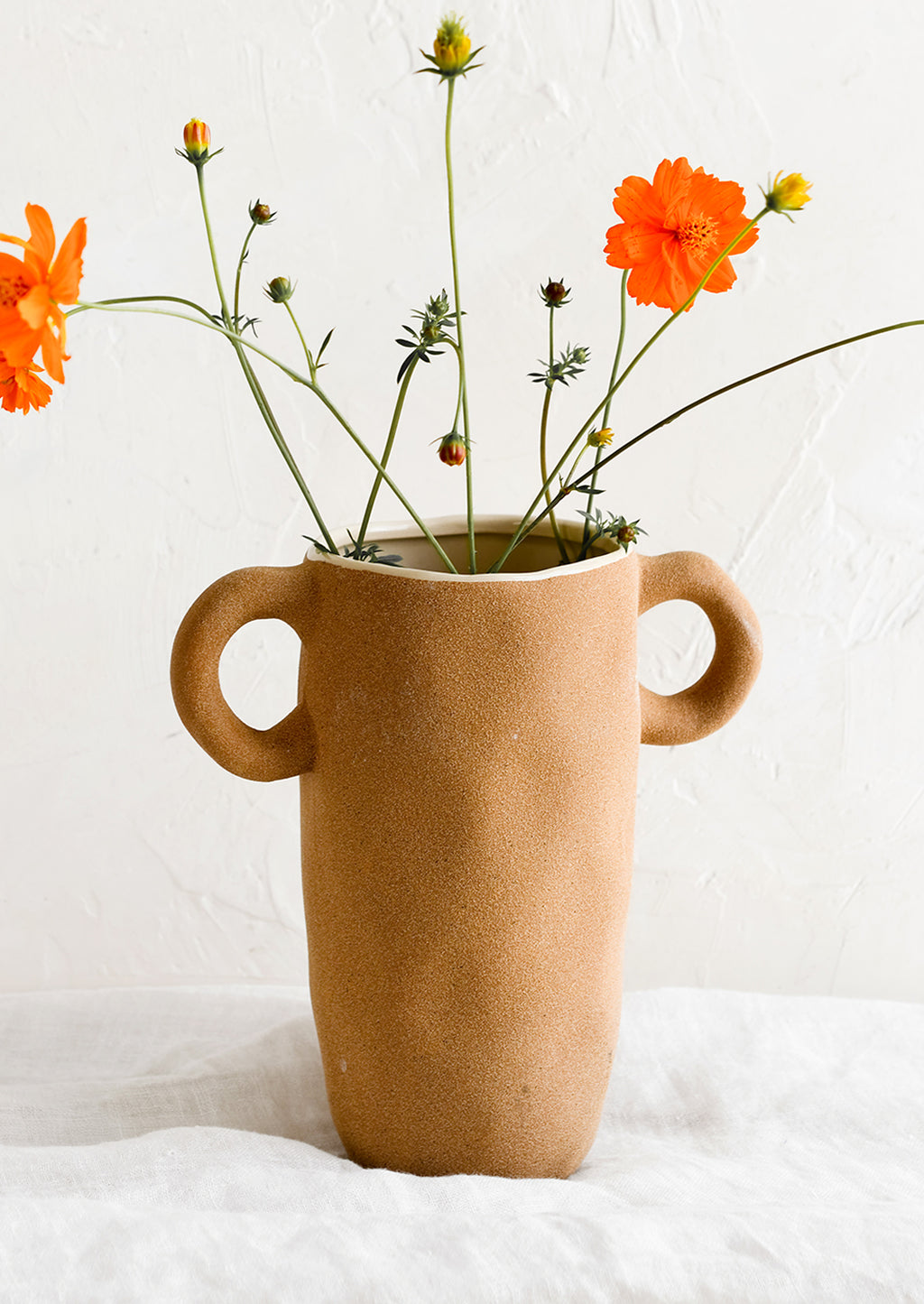 2: A tall brown ceramic vase with orange cosmos.