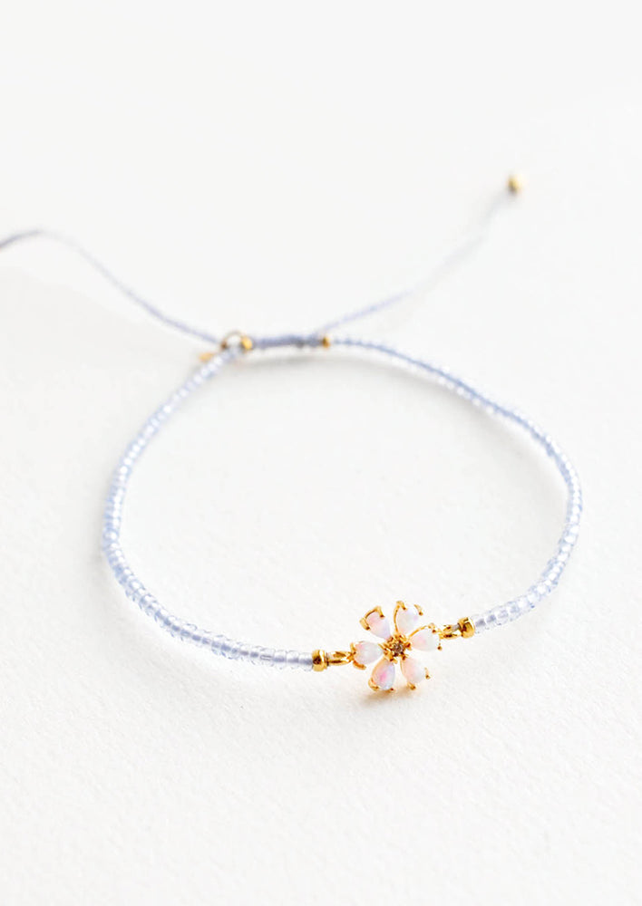 1: A delicate bracelet of pale blue glass beads and a small iridescent gam flower charm. 