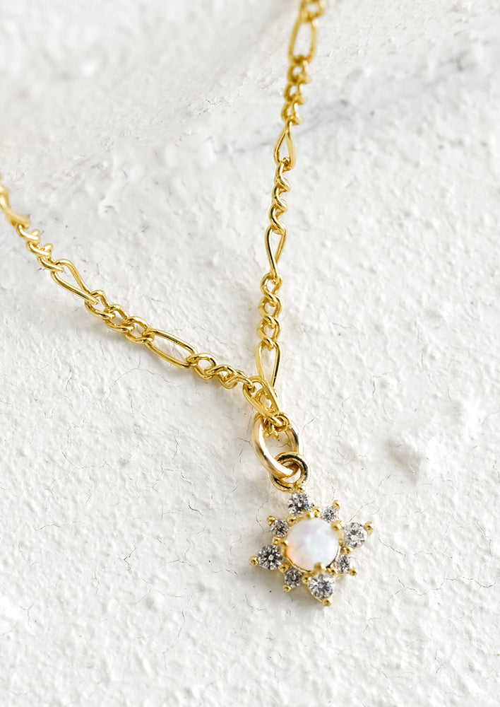 1: A gold figaro chain necklace with opal and crystal north star pendant.