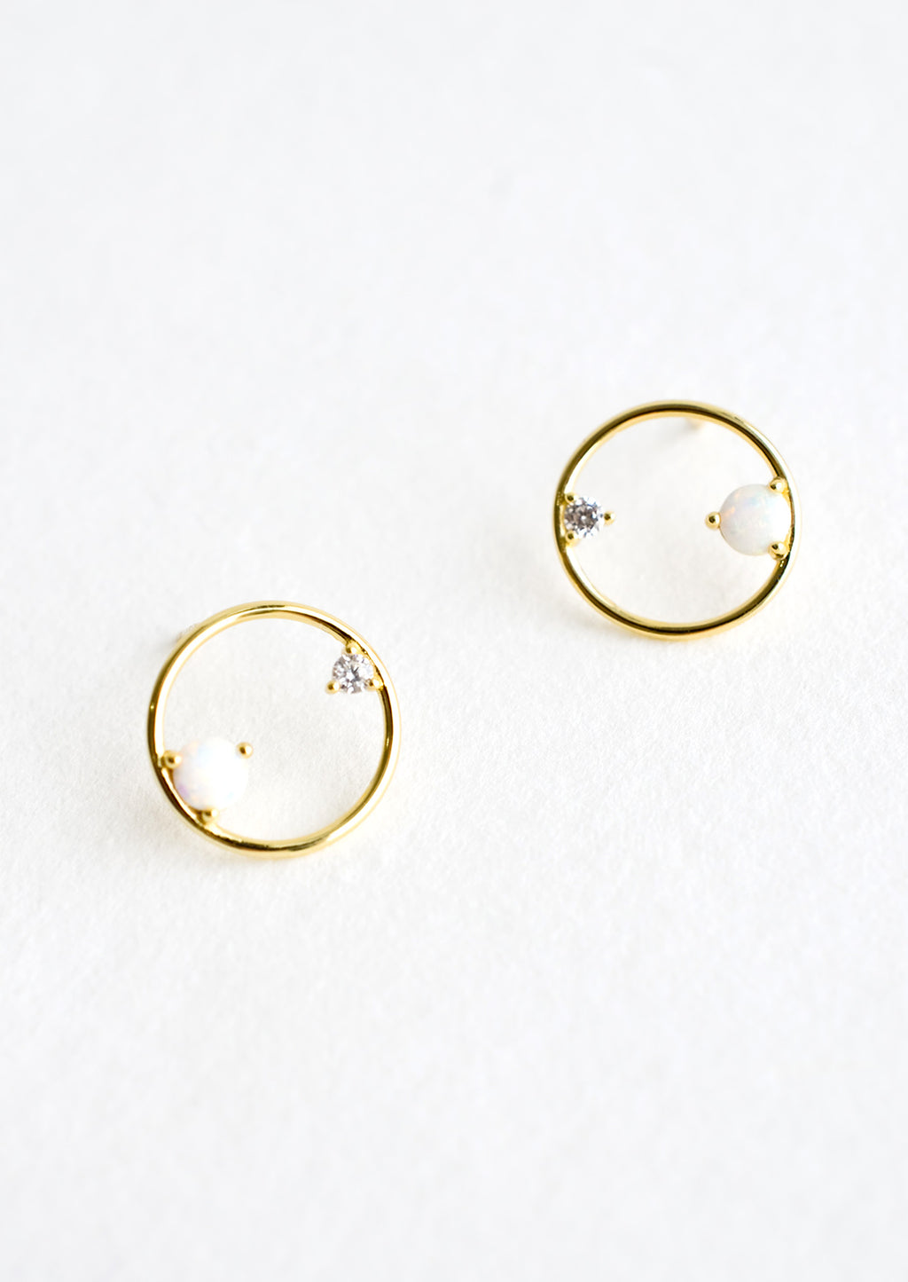 2: A pair of gold stud earrings in the shape of a circle with opal and crystal detailing.