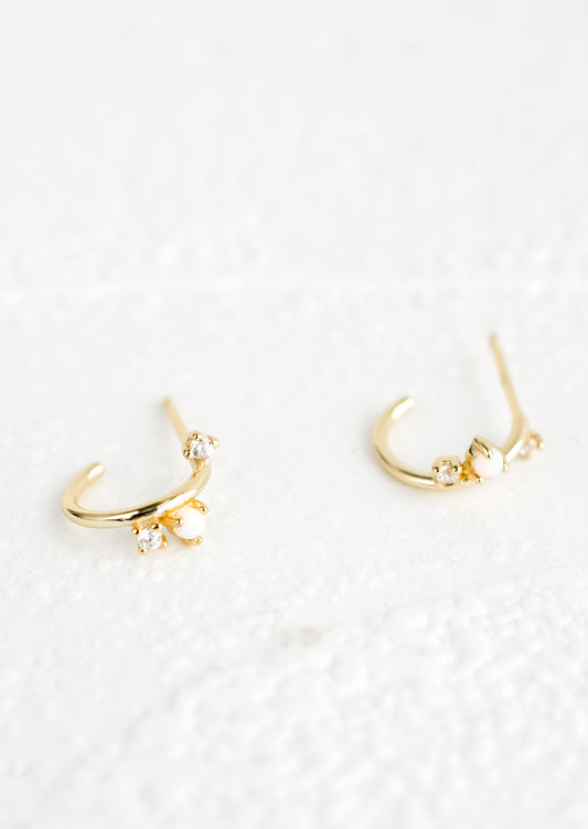 A pair of gold huggie hoop earrings with post back and opal and crystal accents