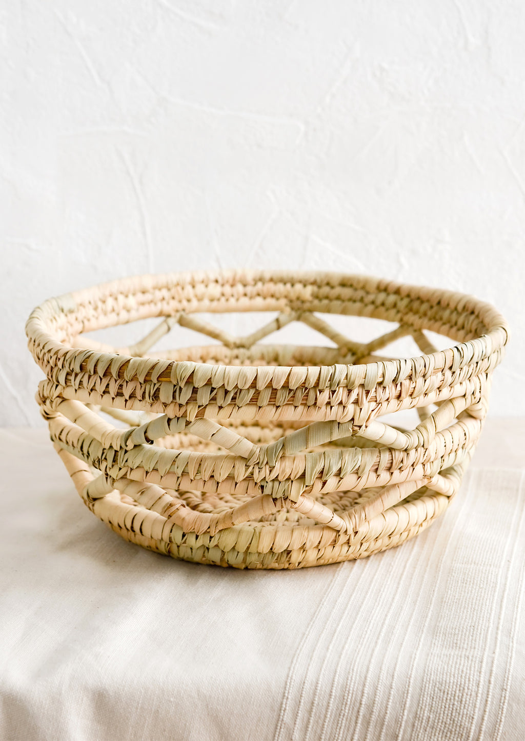 1: A storage bowl/basket made from dried palm leaves in an open weave design.