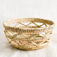 1: A storage bowl/basket made from dried palm leaves in an open weave design.