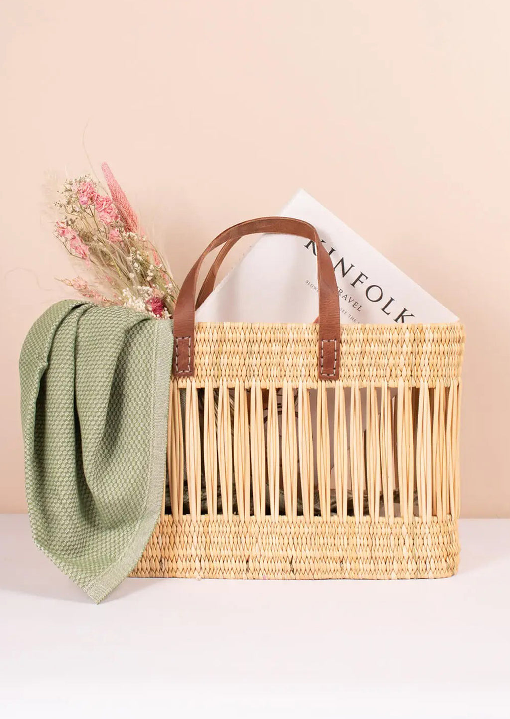 2: A tote-shaped woven reed basket with open air design, brown leather handles.