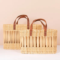 3: A tote-shaped woven reed basket with open air design, brown leather handles.
