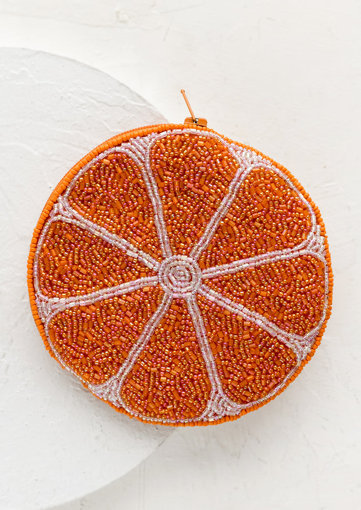 A circle shaped beaded coin pouch in orange slice design.