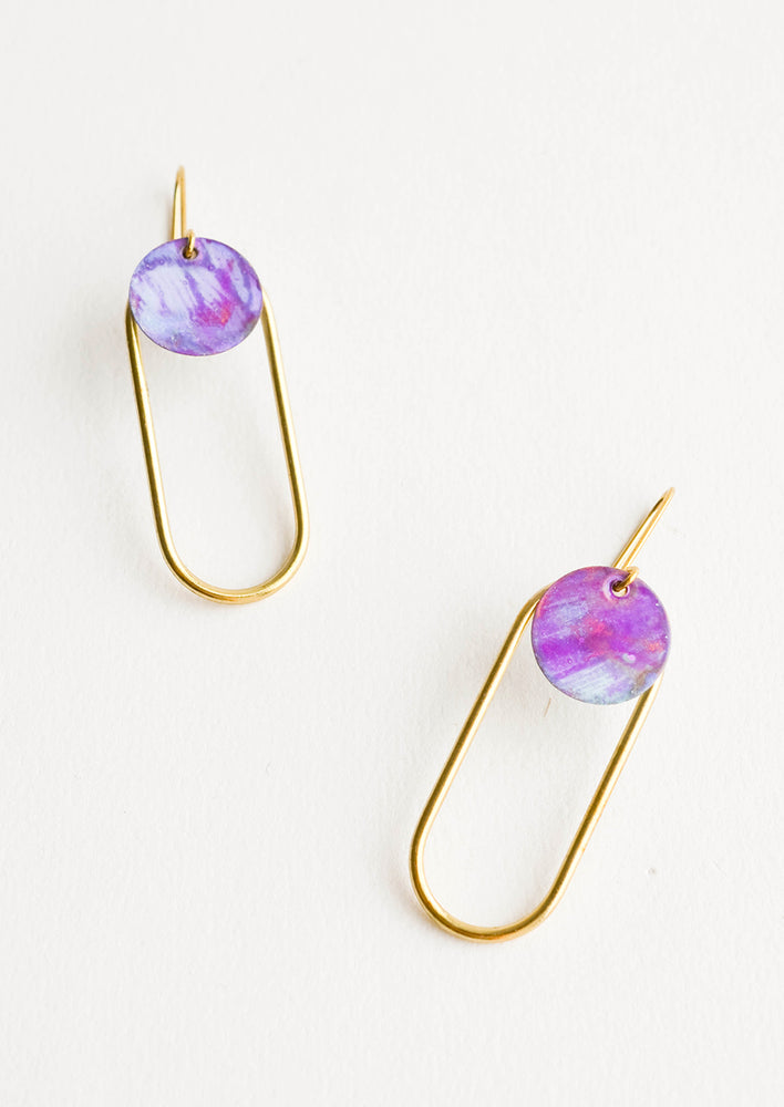 Galactic: Pair of earrings in the shape of a hollow brass oval with a painted purple dot at the top.