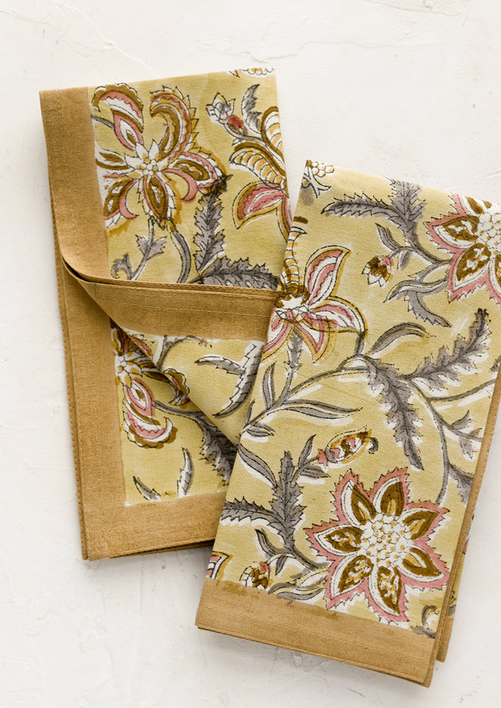 A pair of yellow floral paisley print napkins.
