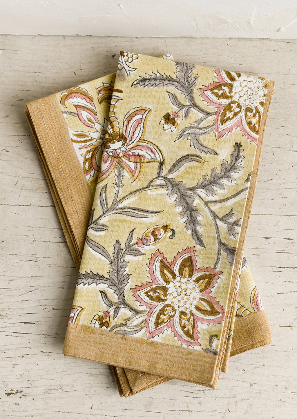 1: A pair of yellow floral paisley print napkins.