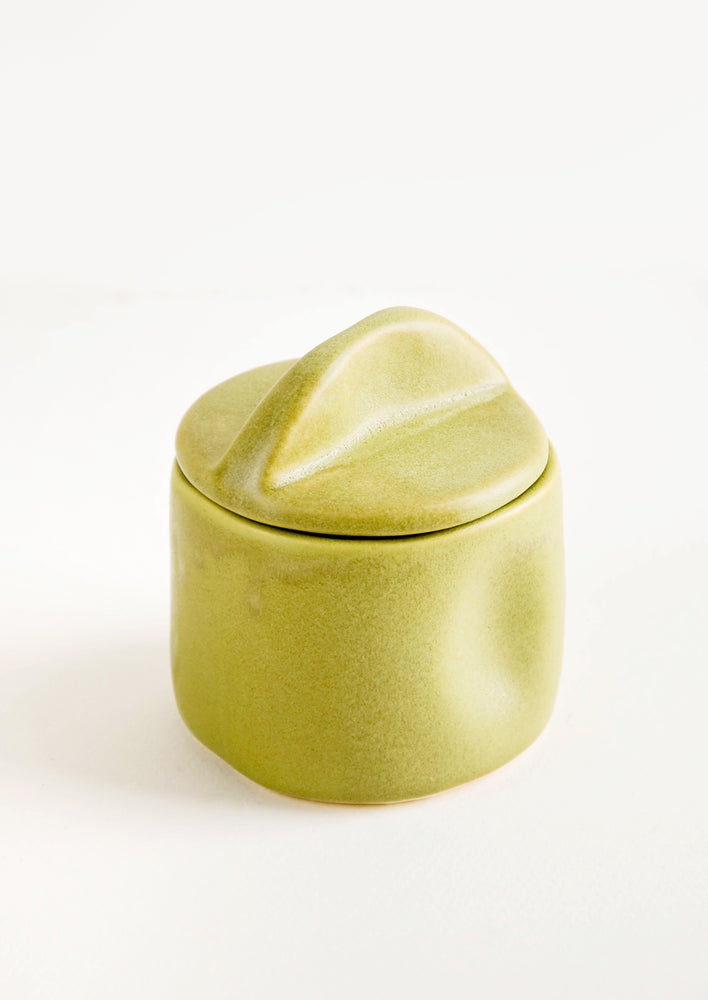A green ceramic jar with handled lid.