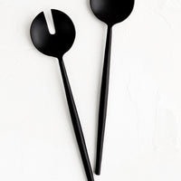 1: A pair of slender, matte black metal serving spoons, with one plain and one notched.