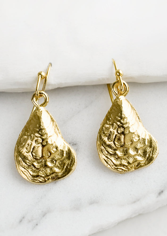 1: A pair of gold earrings in the shape of oyster shell.