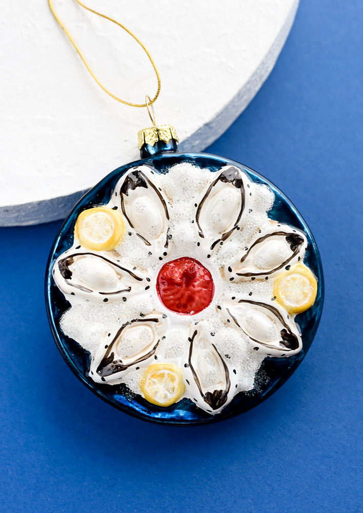 1: A round glass ornament in shape of oysters on a plate of ice.