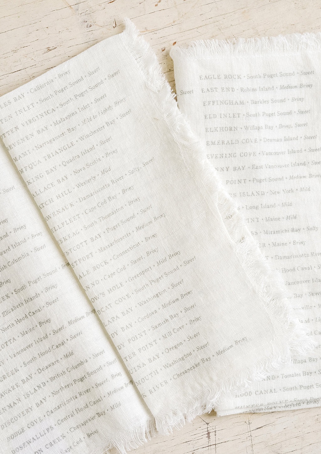 1: White linen napkins with grey text listing out oyster types and their origins.