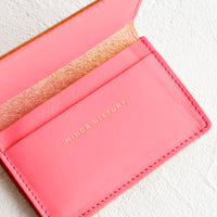 Peony: A bright pink leather card holder wallet with interior sleeve and gold branding.