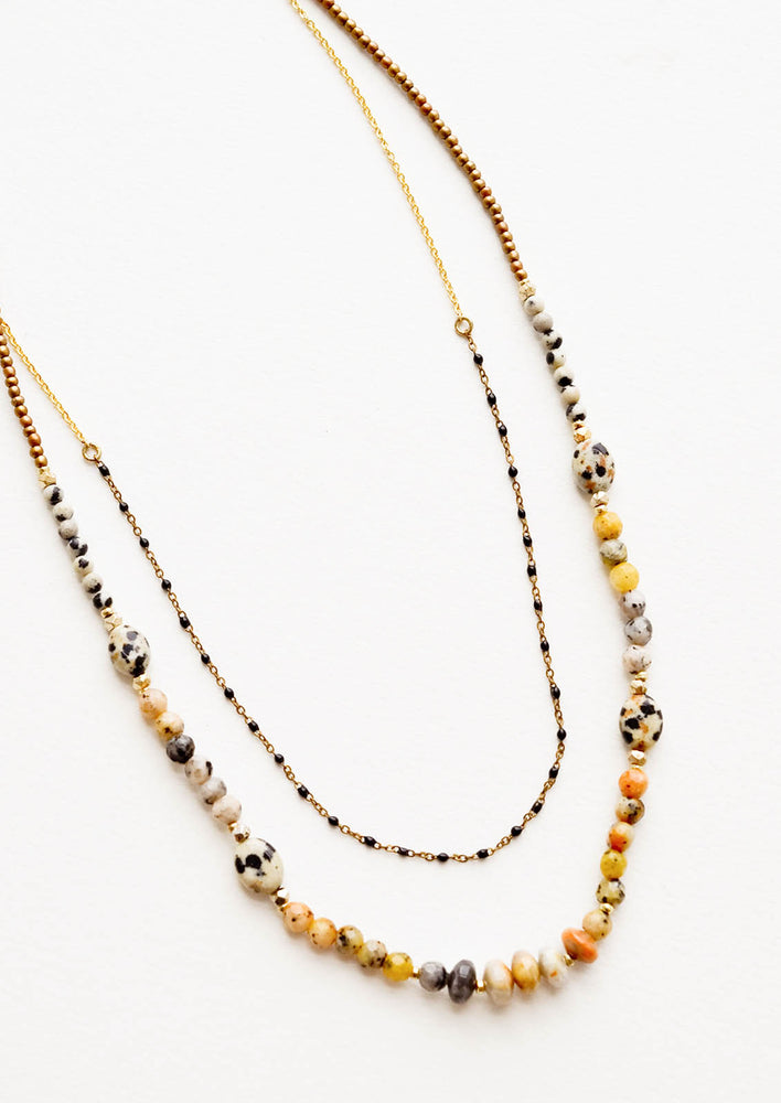 1: Layered beaded necklace with the shorter strand featuring gold chain alternating with black beads, and the longer chain featuring speckled dalmatian jasper beads.