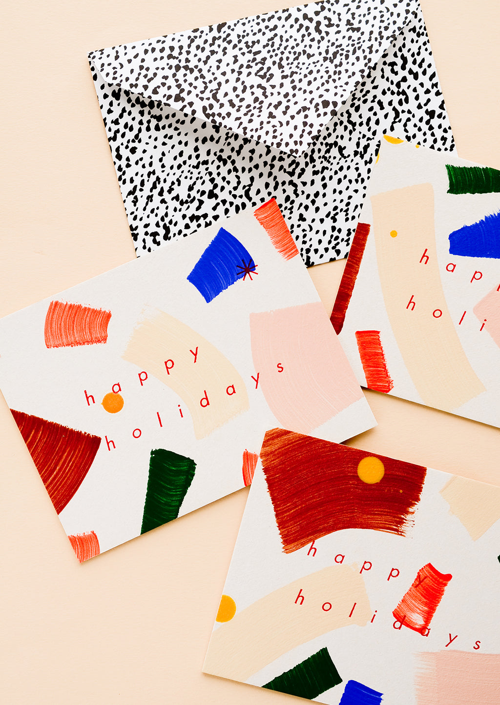 1: Three matching greeting cards with hand-painted brushstrokes and "happy holidays" in red lettering.