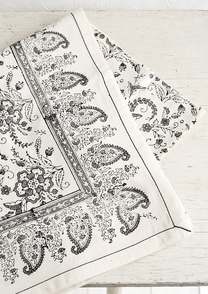 1: A block printed cotton tablecloth with black stitching and grey floral paisley pattern.