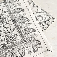 1: A block printed cotton tablecloth with black stitching and grey floral paisley pattern.