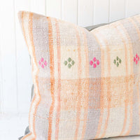3: A pastel orange and lilac gingham pillow with pink and green embroidery accents.