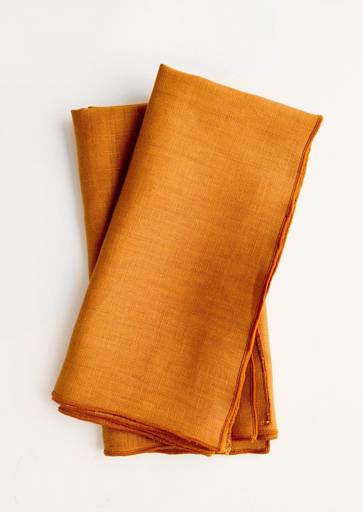 Pair of folded linen napkins in caramel brown with tonal trim