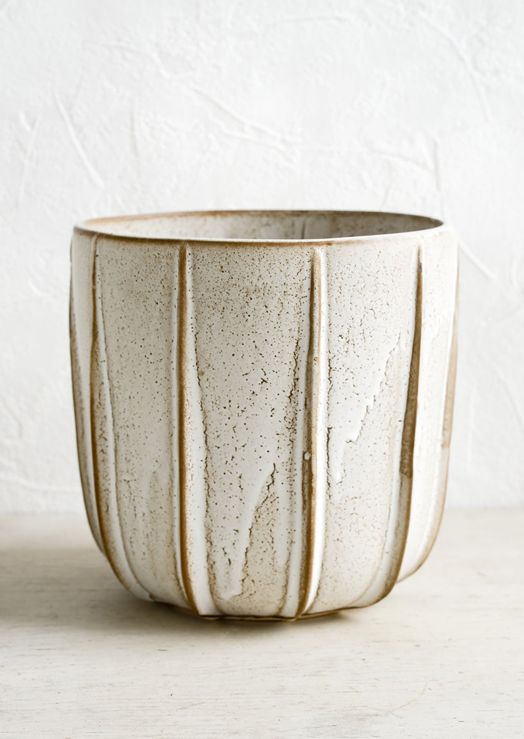 3: A tan ceramic planter with decorative raised grooves.