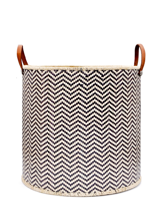 Round storage bin in natural material with allover black zigzag pattern and leather handles