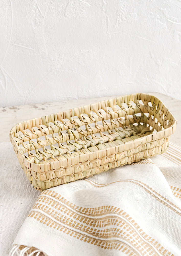 Narrow: A shallow, narrow storage basket made from dried palm leaf.