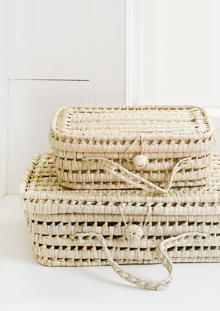 Baskets woven from natural palm leaf in suitcase shape, in small and large sizes.