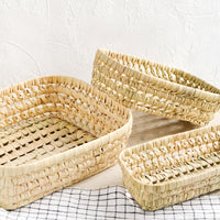 2: Three shallow baskets woven from natural dried palm leaf.