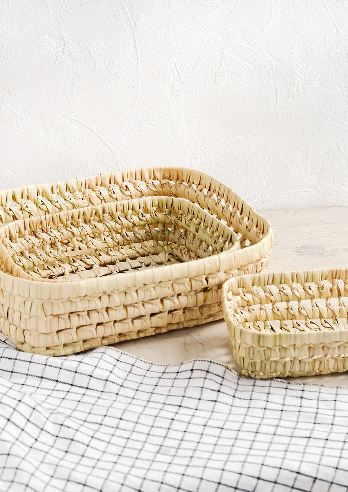 5: A collection of shallow nesting baskets made from palm leaf.