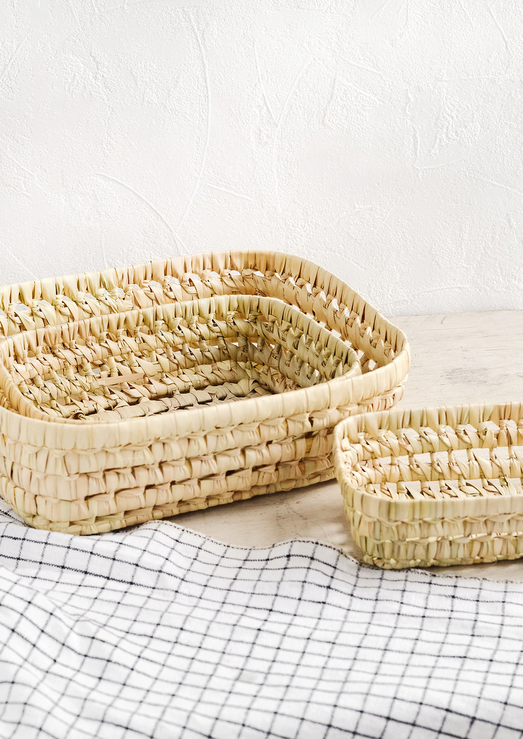 5: A collection of shallow nesting baskets made from palm leaf.