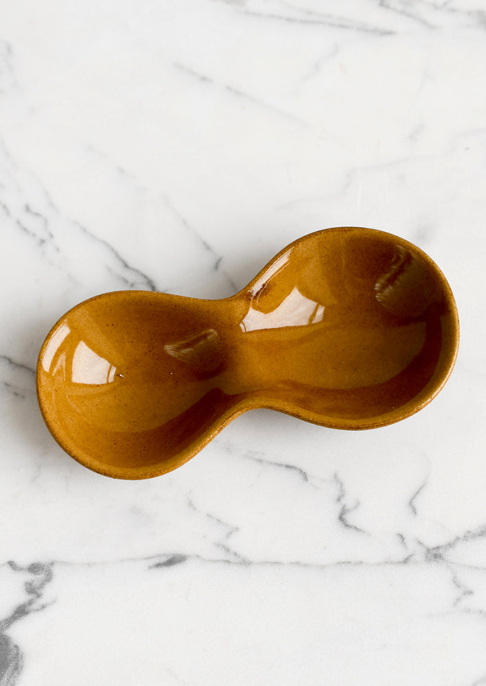 A glossy caramel colored ceramic dish with two wells.