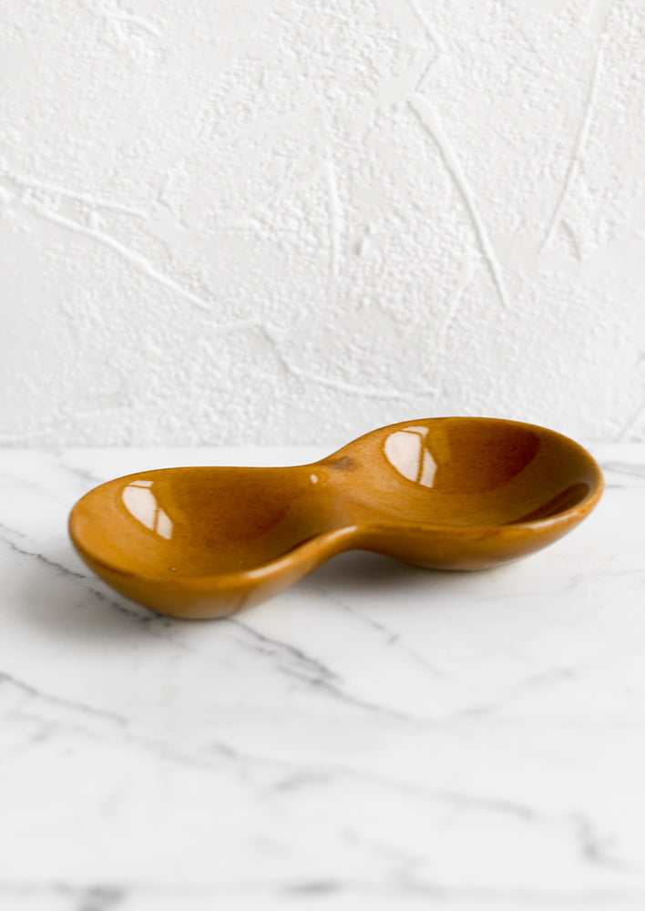 A glossy caramel colored ceramic dish with two wells.