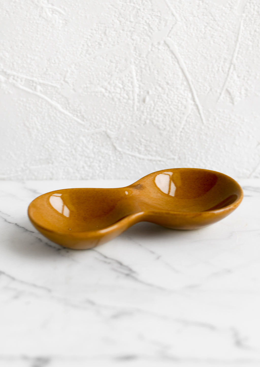 3: A glossy caramel colored ceramic dish with two wells.