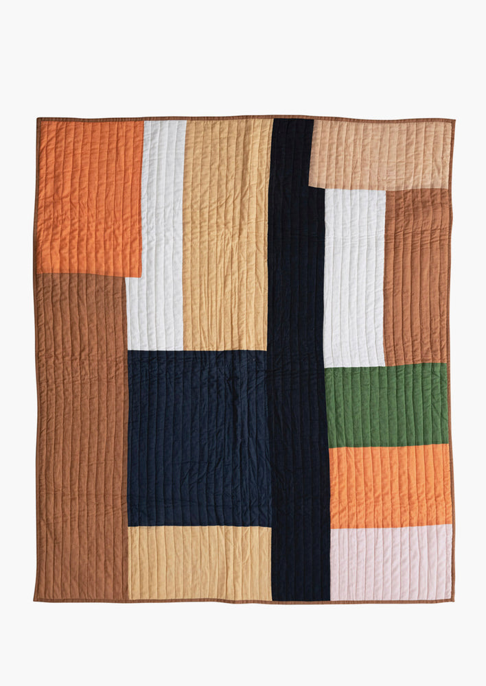 A paneled patchwork quilt in orange and brown tones.