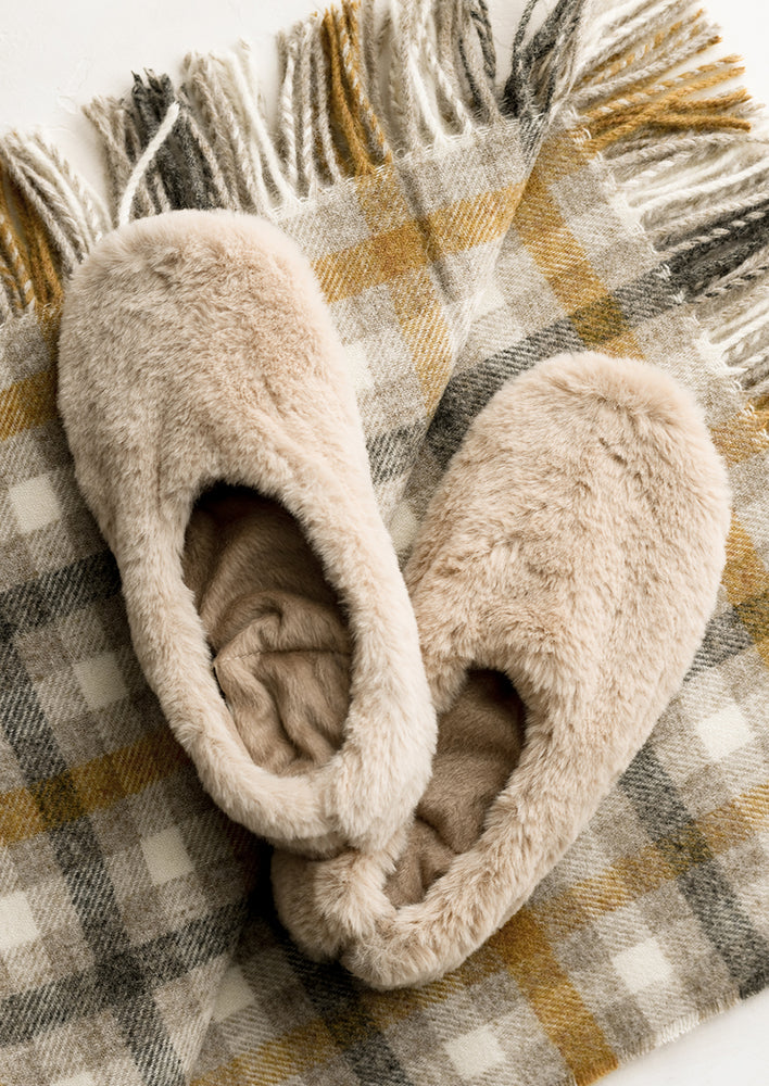 A pair of natural faux fur slippers.