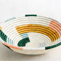 2: A round bowl made from woven sweetgrass in white, multiple pastels and silver.