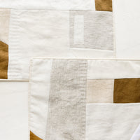 1: A pair of rectangular placemats with patchwork design in natural shades.